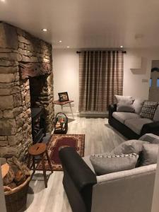 a living room with a couch and a stone fireplace at Eanymore Farm Cottage in Donegal