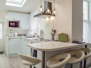 a kitchen with white cabinets and a island with two chairs at Miners Cottage in Girvan
