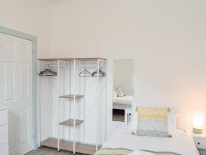 a bedroom with a white cabinet and a bed at Miners Cottage in Girvan