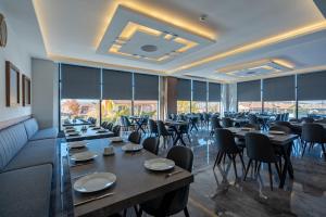 a dining room with tables and chairs and windows at Afyon Regulus Thermal Apart Hotel & Villas in Gazligol