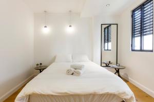 a white bedroom with a large bed with towels on it at AirTLV - Bazel Central Apartment With Balcony in Tel Aviv