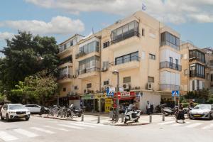 a building on a city street with cars and motorcycles at AirTLV - Bazel Central Apartment With Balcony in Tel Aviv