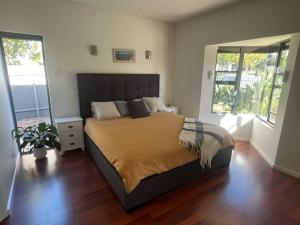 een slaapkamer met een groot bed en 2 ramen bij Stylish 3BR home with outdoor entertaining in Oaklands
