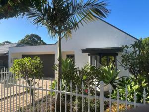 een wit hek voor een huis met een palmboom bij Stylish 3BR home with outdoor entertaining in Oaklands