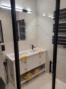 a white bathroom with a sink and a mirror at Apartament Danoe in Łódź +30 photos