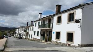 a row of white buildings on a city street at Pensión Boavista in Portomarin