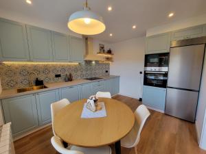 a kitchen with a wooden table and white chairs at Casa de Nuna - Netflix in Cabana de Bergantiños