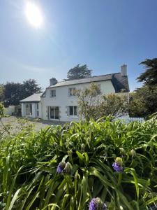 een wit huis met planten ervoor bij Maison de 4 chambres avec jardin clos et wifi a Fouesnant a 3 km de la plage in Fouesnant