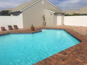 a large blue swimming pool in front of a house at Large villa, walk to the beach in Cape Town