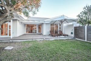 a house with a porch with a bench and an umbrella at Large villa, walk to the beach in Cape Town