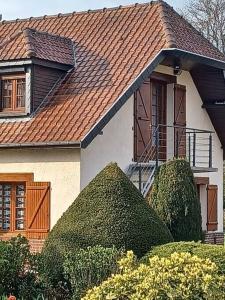 a house with a brown roof and some bushes at Studio Les Trois Clés in Fressenneville