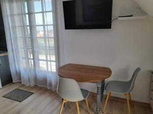 une chambre avec une table, deux chaises et une télévision dans l'établissement Studio Les Trois Clés, à Fressenneville