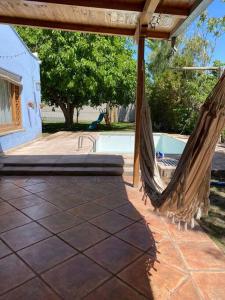 eine Terrasse mit einer Hängematte neben einem Pool in der Unterkunft El Rancho Azul, casona antigua con piscina in Ciudad Lujan de Cuyo