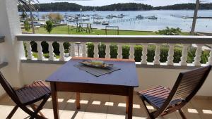 拉布Apartmani Devcic的海港景阳台桌子