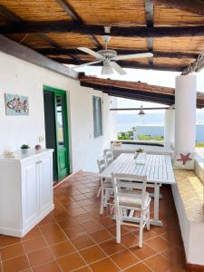 a dining room with a table and chairs and the ocean at Villa Pomelia, Villa nel corso di Santa Marina Salina a 50 mt dal mare in Santa Marina Salina