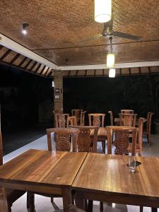 une salle à manger avec des tables et des chaises en bois dans l'établissement Sujana Homestay, à Ubud