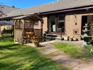 uma casa com uma mesa de piquenique e um guarda-chuva em Drummond Neuk - Pets Welcome! em Inverness