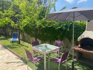 uma mesa e cadeiras com um guarda-sol num quintal em 3 Pièces climatisé en rez de jardin avec piscine em Villeneuve-Loubet