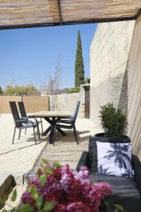 - une terrasse avec une table, des chaises et des fleurs dans l'établissement Maison la Cassine - Centre Doué la Fontaine - Proche Zoo, à Doué-la-Fontaine