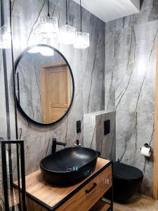 ein Bad mit einem schwarzen Waschbecken und einem Spiegel in der Unterkunft Apartament Jodełka na Powiślu in Warschau