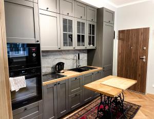 eine Küche mit grauen Schränken und einem Holztisch in der Unterkunft Apartament Jodełka na Powiślu in Warschau