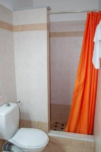 a bathroom with a toilet and an orange shower curtain at Phyllida Guest House - A2 in Zakharo