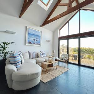 una sala de estar con muebles blancos y ventanas grandes. en Merlin Farm Cottages short walk to Mawgan Porth Beach and central location in Cornwall en Mawgan Porth