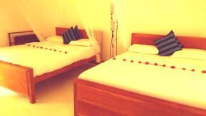 a bedroom with two beds with red accents on them at Marvellous Inn in Ella