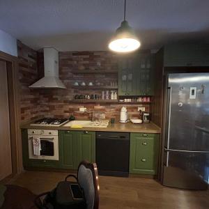 uma cozinha com armários verdes e um frigorífico de aço inoxidável em GorkyHouseUrla em Ildır