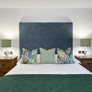 ein Schlafzimmer mit einem großen Bett mit grüner Bettwäsche und Kissen in der Unterkunft Merlin Farm Cottages short walk to Mawgan Porth Beach and central location in Cornwall in Mawgan Porth
