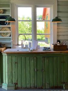 a green counter in a kitchen with a window at Villa Leonore: Sommerhus m/strandlinje på Helgøya in Ringsaker
