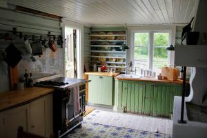 a kitchen with green cabinets and a stove at Villa Leonore: Sommerhus m/strandlinje på Helgøya in Ringsaker