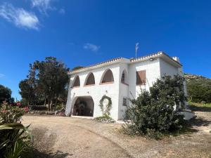 un edificio blanco con un arco en un camino de tierra en Villa Clementina - Sant'Antioco en SantʼAntìoco