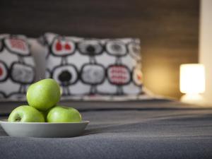a bowl of green apples sitting on a bed at Apartaments Atzavara in Calella
