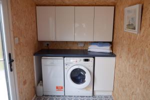 een wasmachine en droger in een keuken met witte kasten bij The Garden Suite Holt in Holt