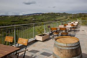 a balcony with tables and chairs and a barrel at Hotel Kozana in Dobrovo
