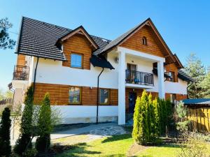 a wooden house with a black roof at Apartamenty Czerwone Korale in Cielimowo