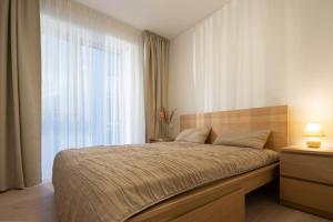 ein Schlafzimmer mit einem Bett und einem großen Fenster in der Unterkunft Sunset Apartment in Juodkrantė