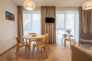 ein Wohnzimmer mit einem Tisch und Stühlen im Zimmer in der Unterkunft Sunset Apartment in Juodkrantė