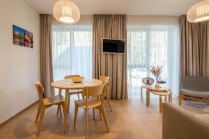 a living room with a table and chairs in a room at Sunset Apartment in Juodkrantė