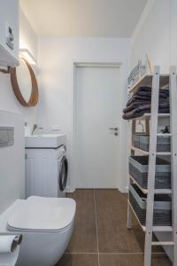 a bathroom with a toilet and a sink and a shelf at Sunset Apartment in Juodkrantė