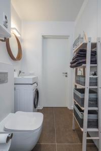 a bathroom with a toilet and a sink and a shelf at Sunset Apartment in Juodkrantė +18 photos
