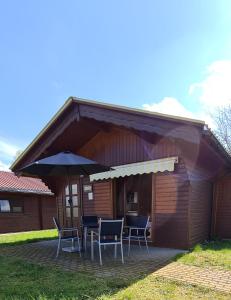 a house with a table and chairs and an umbrella at Mobilheim und Blockhaus mit Seeblick in Sternberg