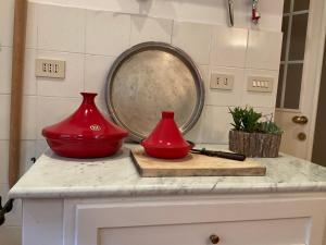 deux vases rouges assis sur un comptoir avec miroir dans l'établissement La casa di Bedelia, à Capodimonte