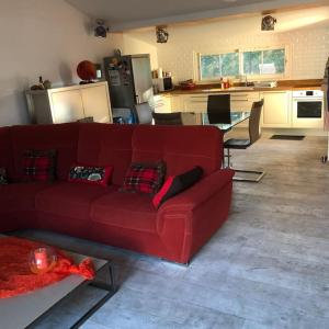 a living room with a red couch and a kitchen at Saint Vivien de Médoc: jolie maison médocaine in Saint-Vivien-de-Médoc