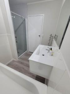 a white bathroom with a sink and a shower at Aucktons house in Auckland