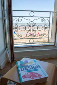 um livro sentado numa mesa em frente a uma janela em Panoramic Mulberry Beach plendid family apartment em Asnelles