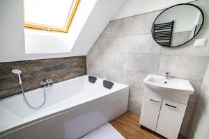 a bathroom with a tub and a sink and a mirror at Rezydencja Klonowa in Ober Wüstegiersdorf