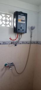 a television on the wall of a bathroom with a hose at Rindu Homestay in Undisan