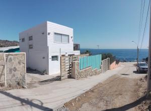 uma casa branca no lado de uma estrada ao lado do oceano em Casa blanca bella vista em Tongoy